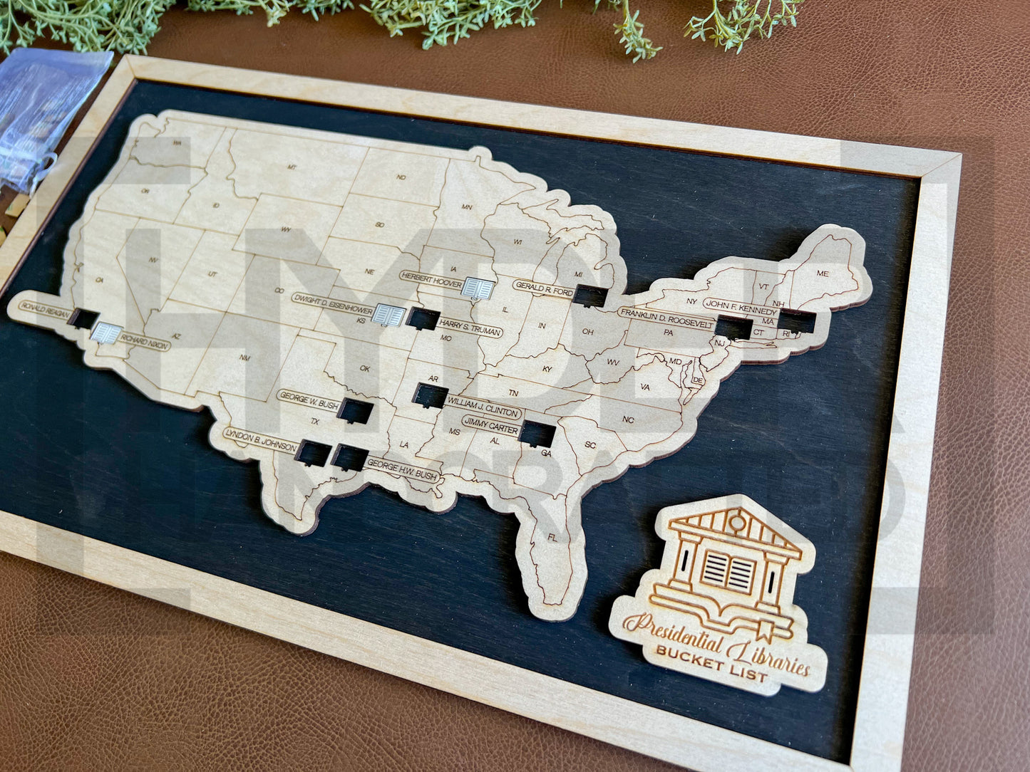 A wall-mounted map showcasing the locations of Presidential Libraries in the United States with a wooden frame and markers. The map is labeled with 'Bucket List' and 'Presidential Libraries'. Black stain background