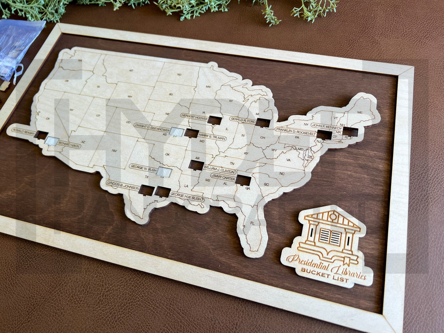 A wall-mounted map showcasing the locations of Presidential Libraries in the United States with a wooden frame and markers. The map is labeled with 'Bucket List' and 'Presidential Libraries'. dark walnut background
