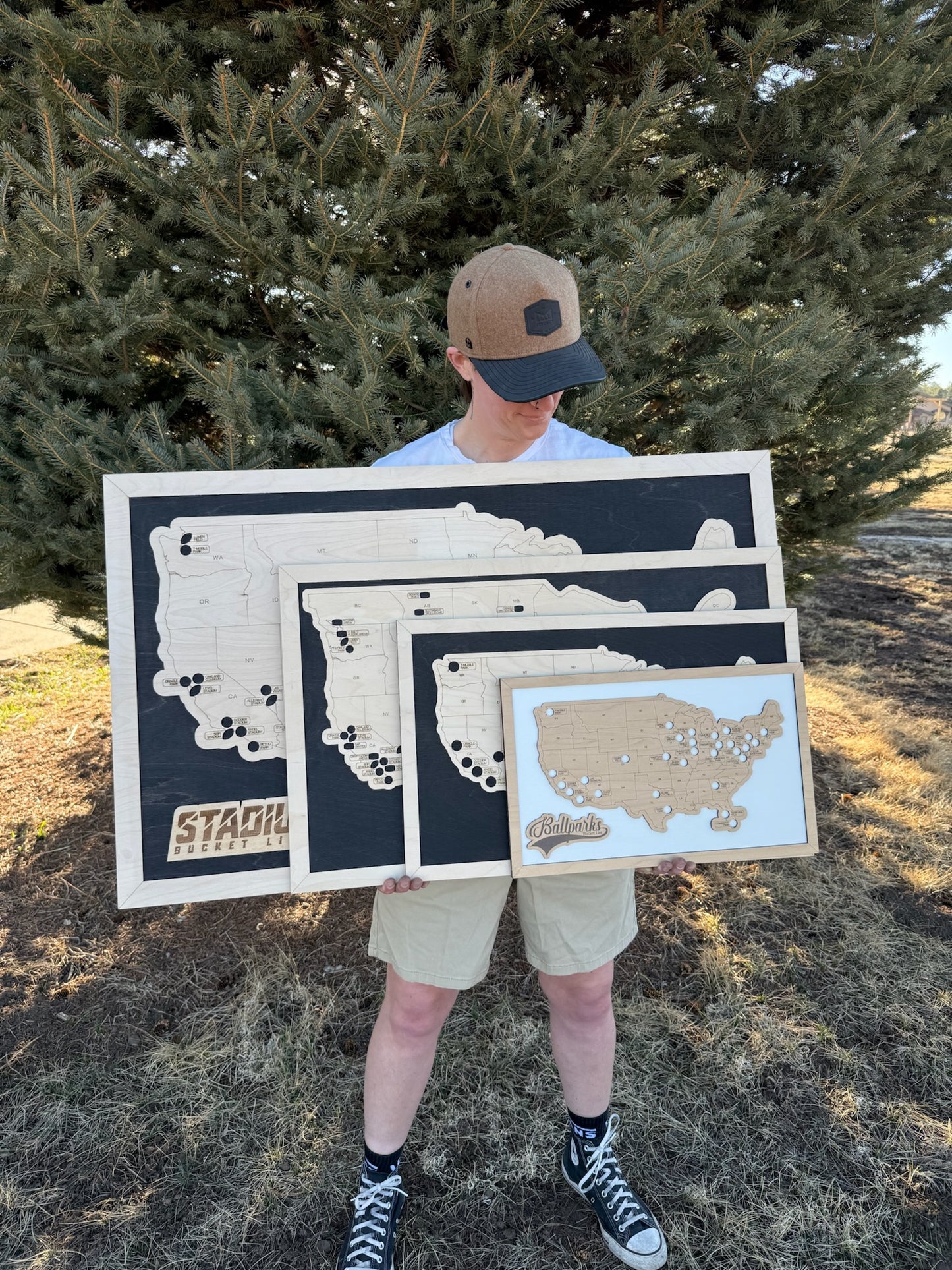 Person holding wooden maps of different states outdoors, multiple sizes