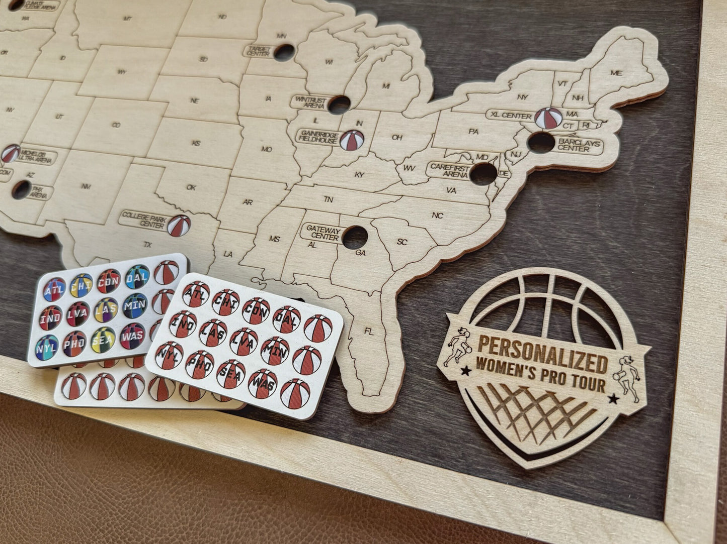Wooden map of the United States with personalized women's pro tour stickers and a logo on a wooden surface.