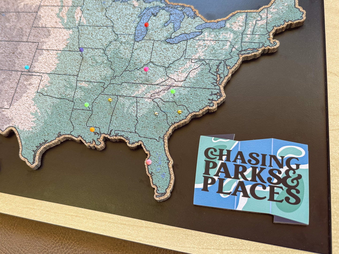 Map of the United States with pins and a card titled 'Chasing Parks & Places' on a dark surface.