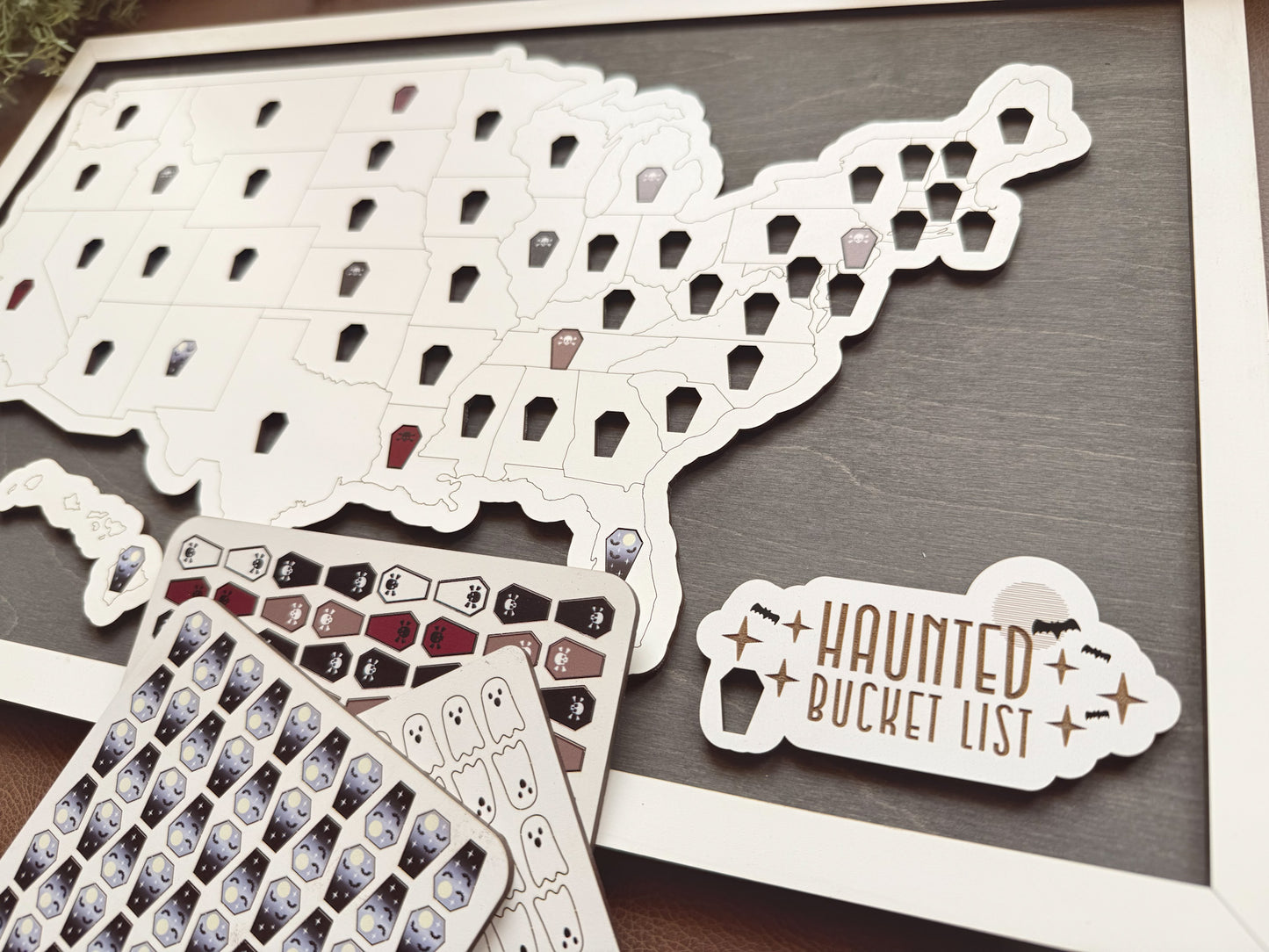 Decorative elements including a coffin-shaped cutout, ghost stickers, and 'Haunted Bucket List' on a dark surface.
