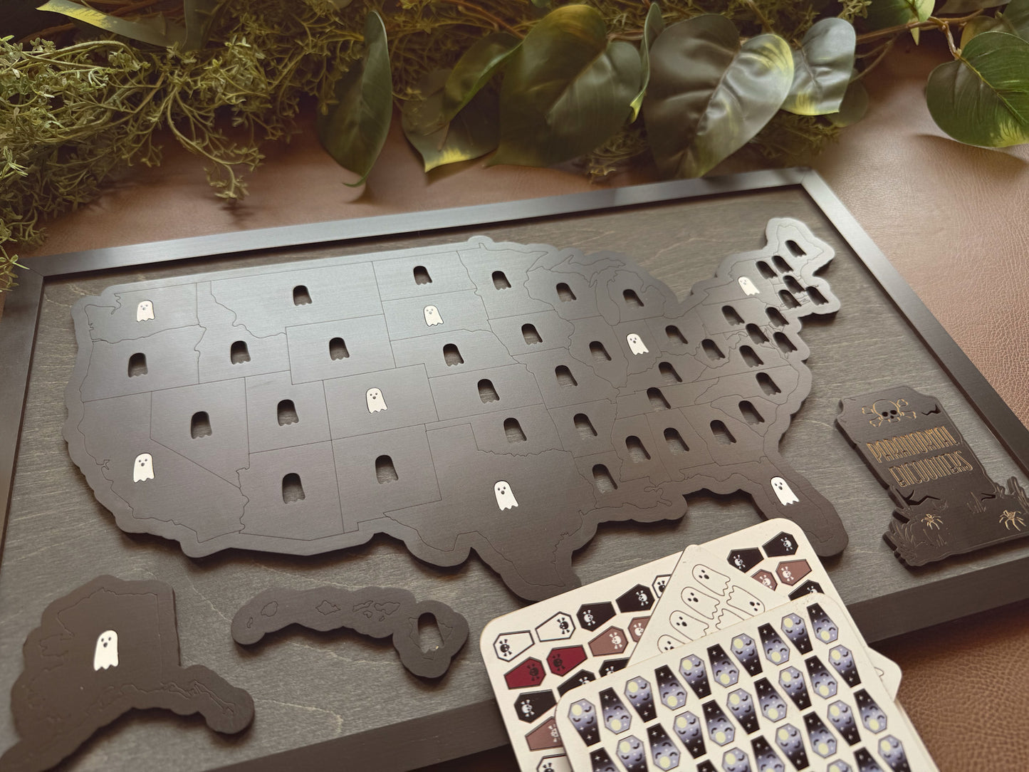 Map of the United States with ghost symbols and a card with more ghost symbols on a wooden surface.