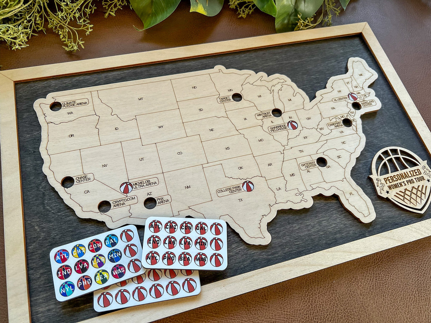 Wooden map of the United States with pins and sticker sheets on a wooden board.