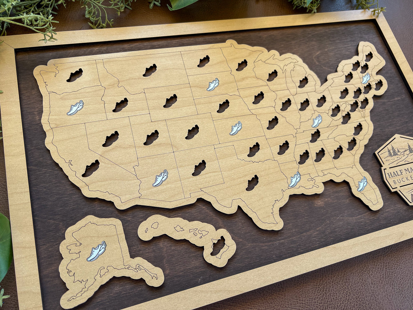 Wooden map of the United States with cut-out states and pins on a wooden board.
