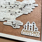 A map showcasing airport locations with plane tokens, labeled 'Airport Bucket List', positioned on a wooden surface with a natural brown border.