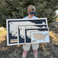 Person holding wooden maps of different states outdoors, showing 4 different map sizes.