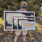 Person holding a wooden map of the United States outdoors