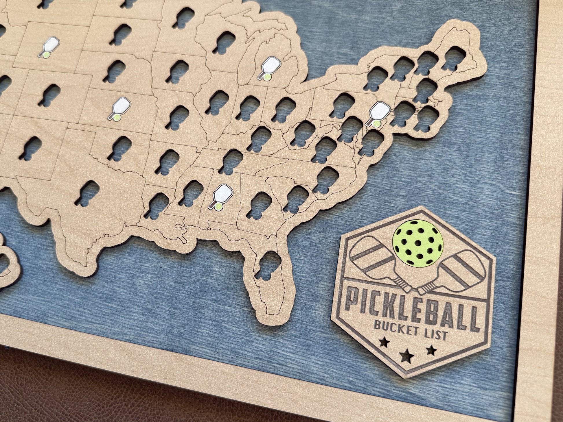 Map of the United States with pickleball court locations and a Pickleball Bucket List badge. close up. blue stain background