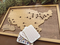 Wooden map of the United States with cut-out states and cards featuring baseball stadium logos.