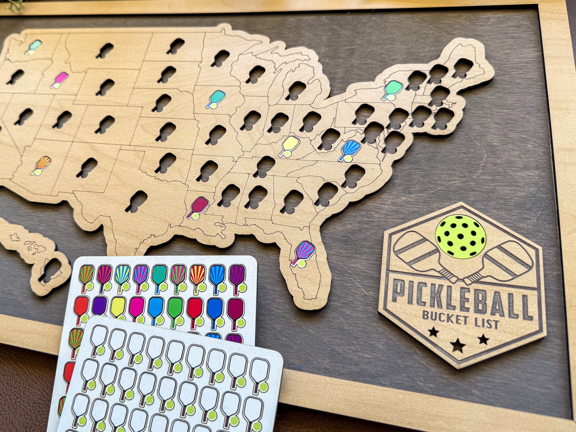 Wooden map of the United States with pickleball-related items on a wooden surface. close up