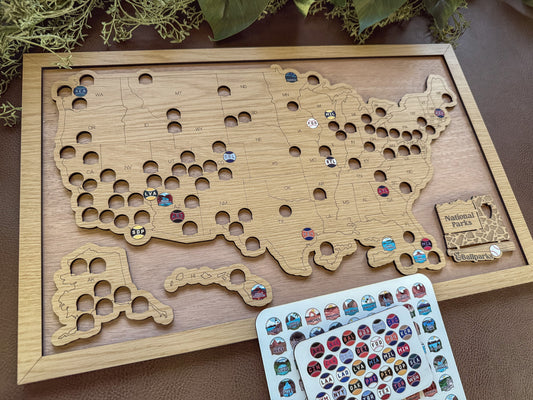 Wooden map of the United States with pins and a card of stickers on a wooden surface.