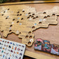 Wooden map of the United States with animal sticker tokens and zoo bucket list sign on a wooden surface.