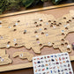 Wooden map of the United States with cut-out states and animal stickers on a wooden surface.