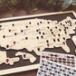 Map of the United States with pins and a set of coffin tokens on a wooden surface.
