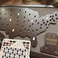 Map of the United States with cut-out states on a wooden surface, accompanied by a card of tokens for tracking