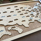 Wooden map of the United States with cut-out states, each featuring a fish illustration, on a wooden surface.