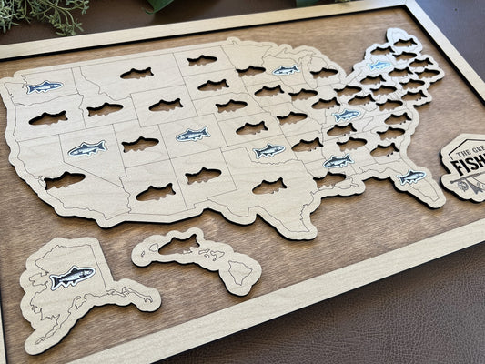 Wooden map of the United States with cut-out states, each featuring a fish illustration, on a wooden surface.