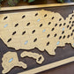 Wooden map of the United States with cut-out states and pins on a wooden board.